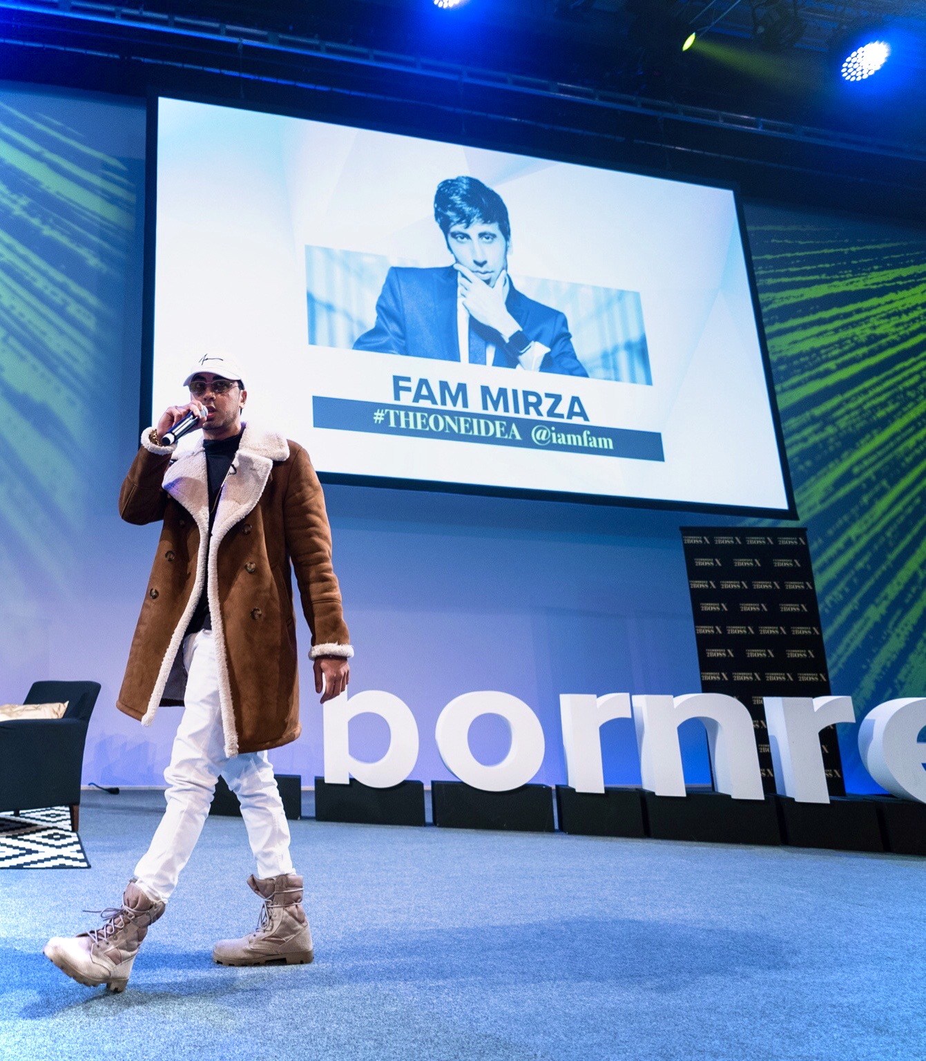 Fam Mirza speaking into a microphone on a blue-lit stage
