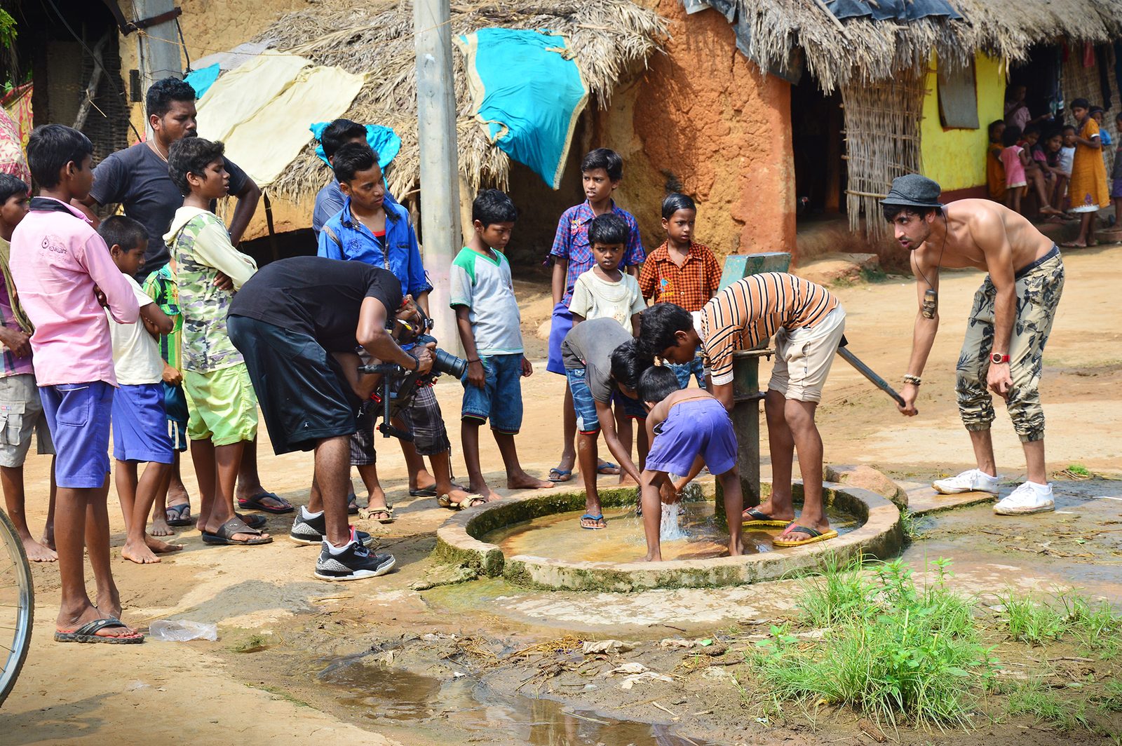 Fam Mirza with children and a film crew beside an outdoor water basin